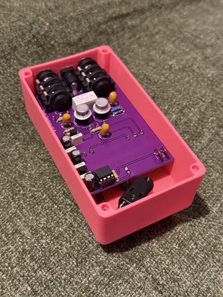 picture of pink electronic guitar pedal, opened, showing interior electronics
